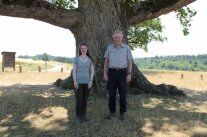 Frau und Mann in Forstkleidung stehen vor einem Baum